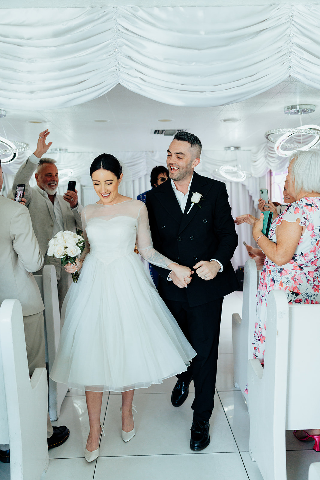 Bride and groom smiling and holding hands after their ceremony at The Little White Wedding Chapel