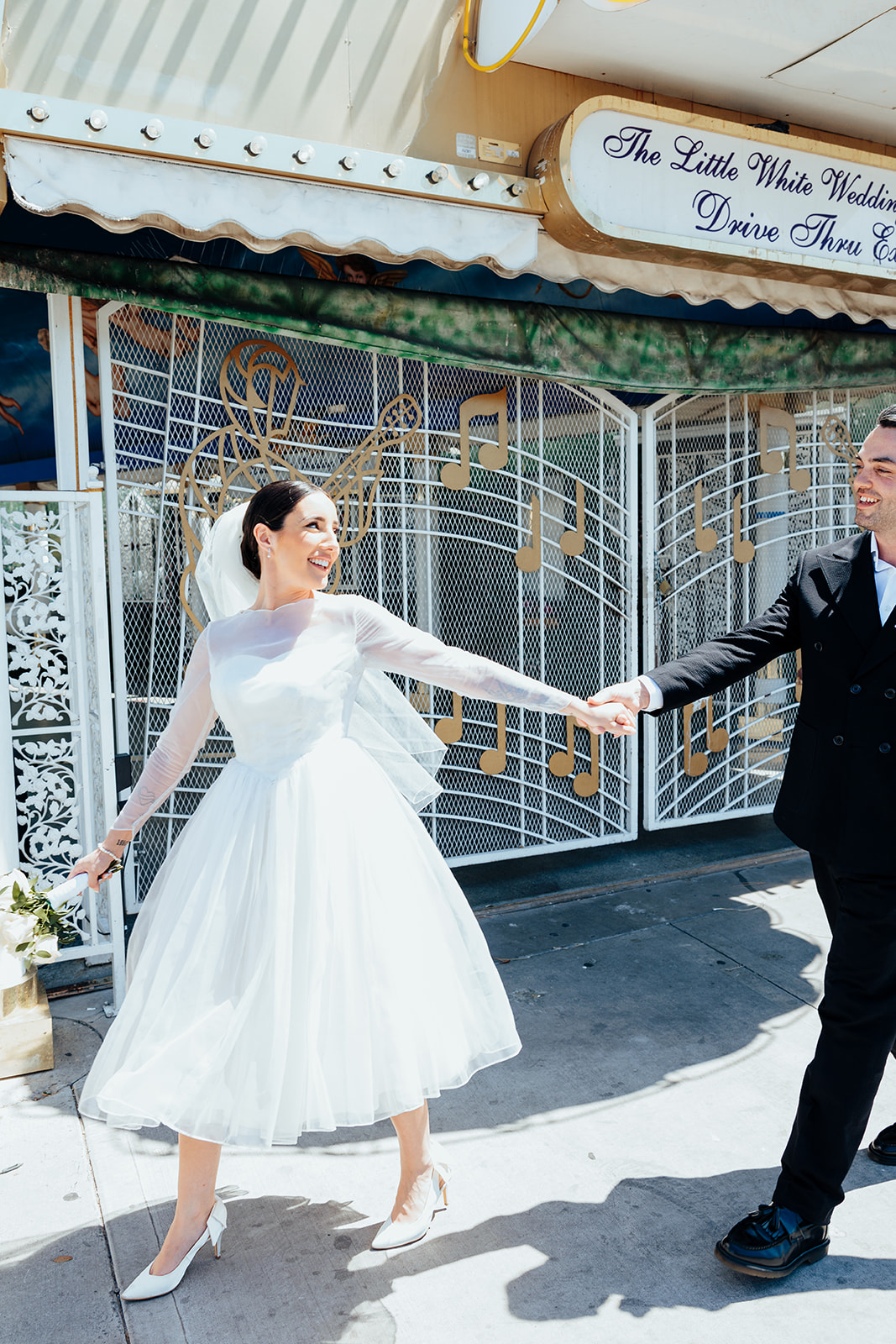 Bride and groom hold hands joyfully outside The Little White Wedding Chapel