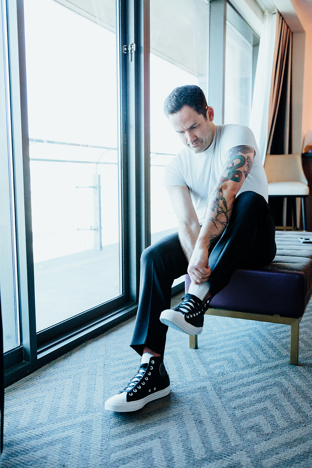 Groom putting on black sneakers while preparing for a Las Vegas wedding.