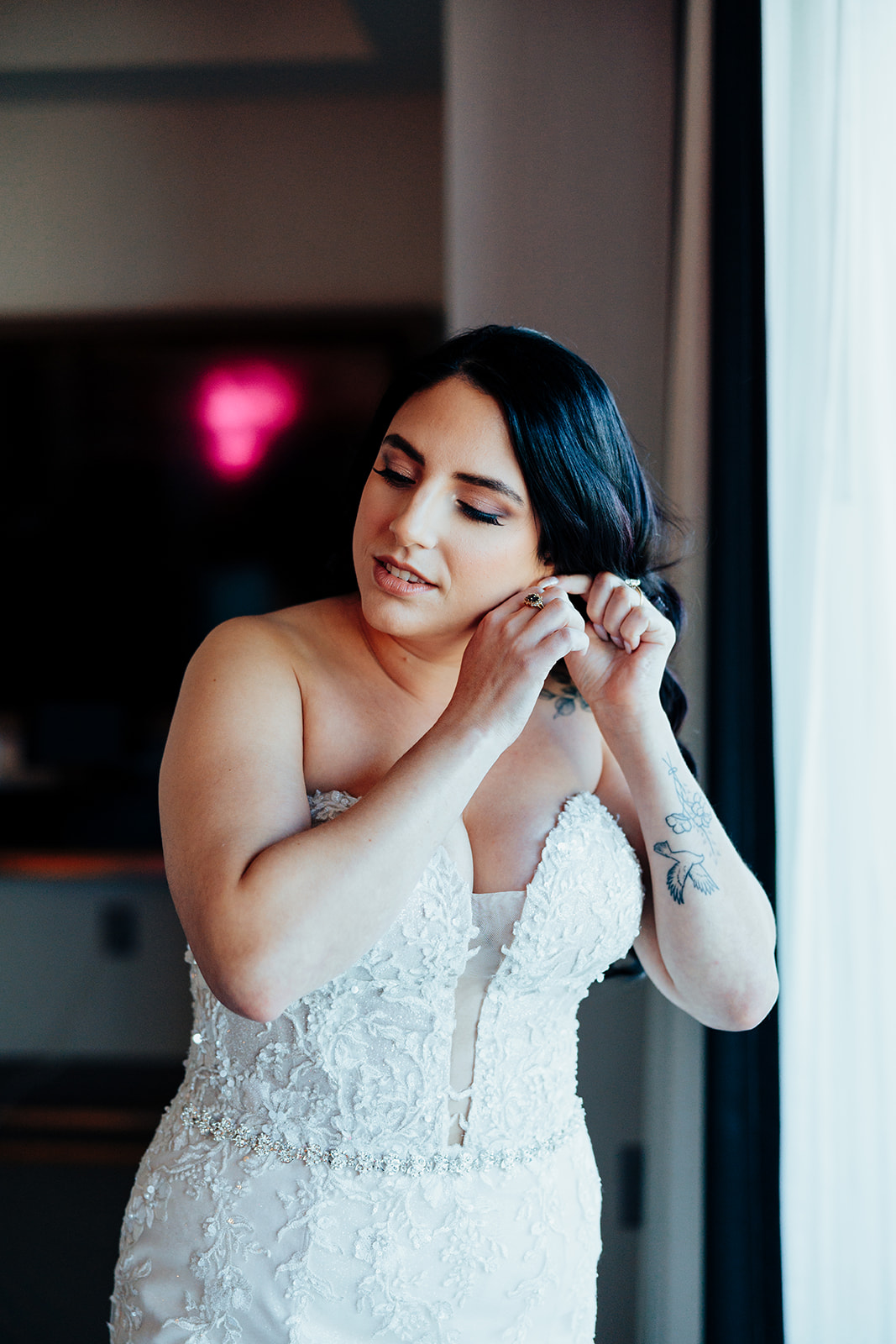 Bride adjusting earrings in hotel suite on wedding day