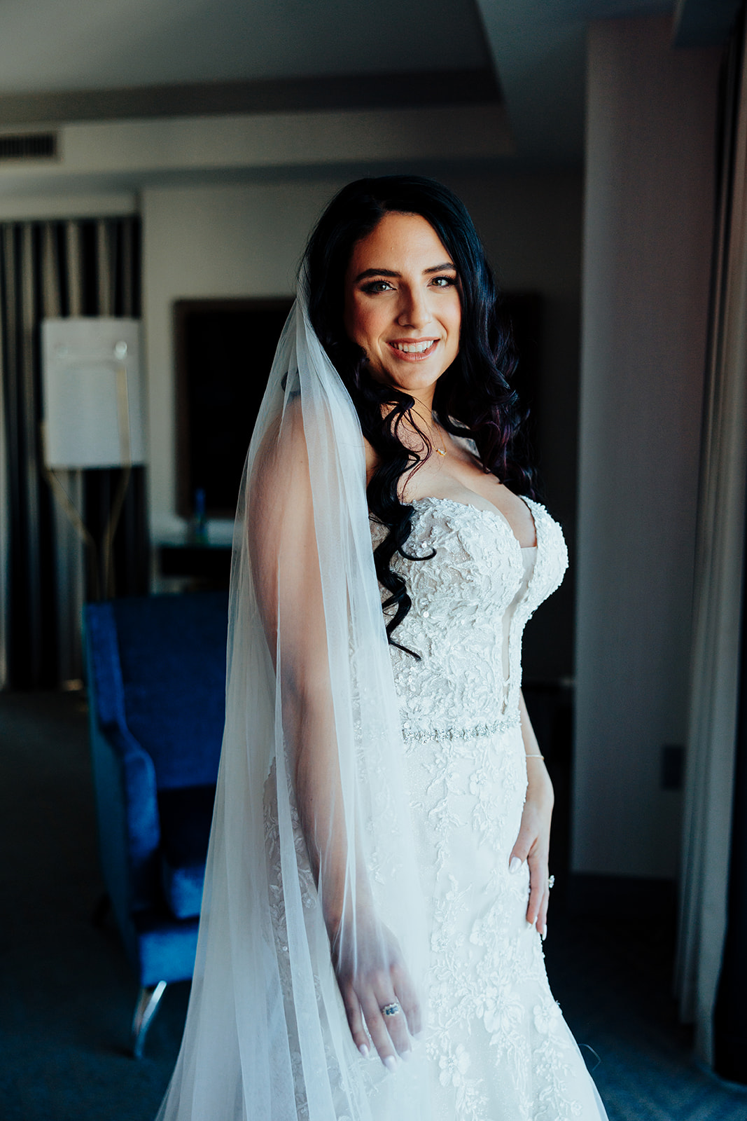 Bride smiling in lace gown and veil in Las Vegas hotel suite