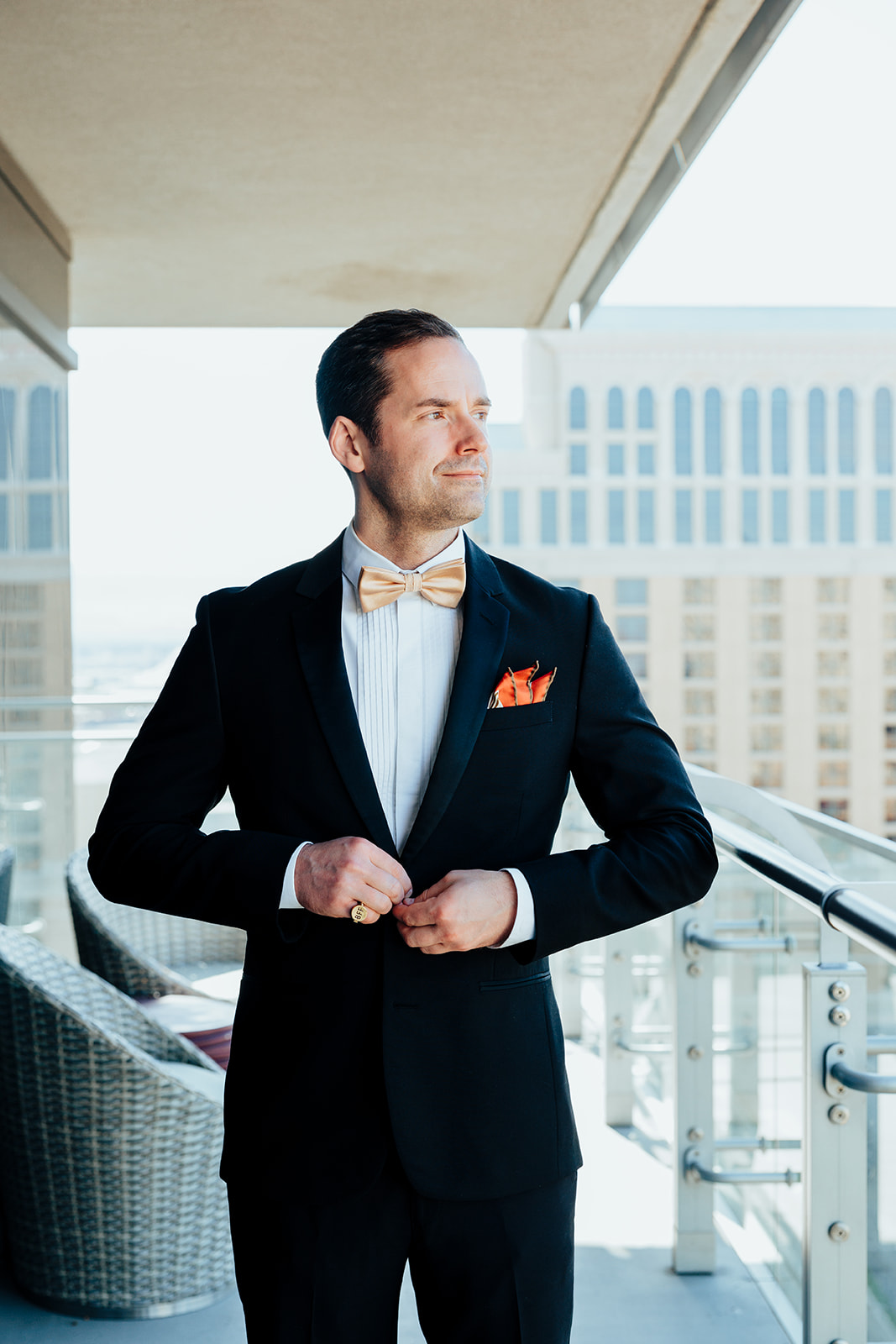 Groom adjusting bow tie on balcony with Las Vegas Strip in the background