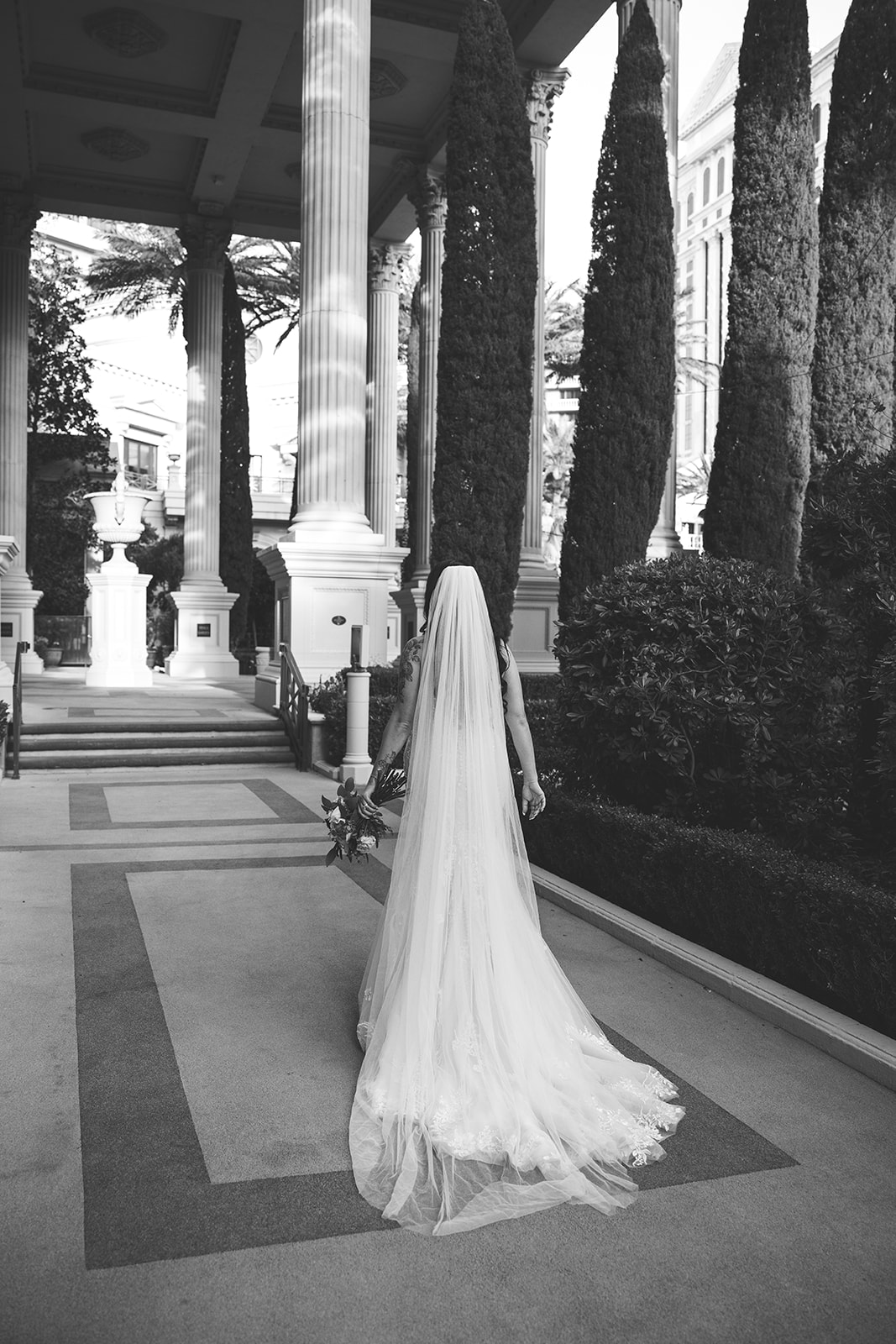 Black-and-white image of bride walking through elegant garden at Caesars Palace