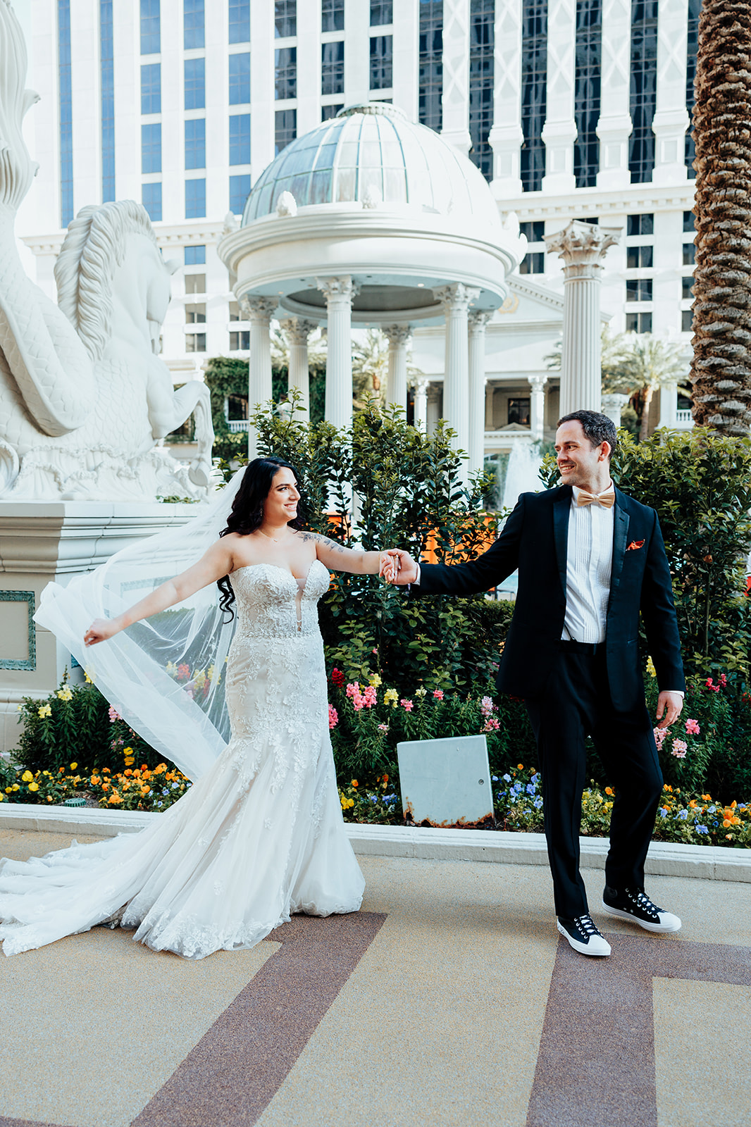 Playful couple holding hands near iconic Caesars Palace dome