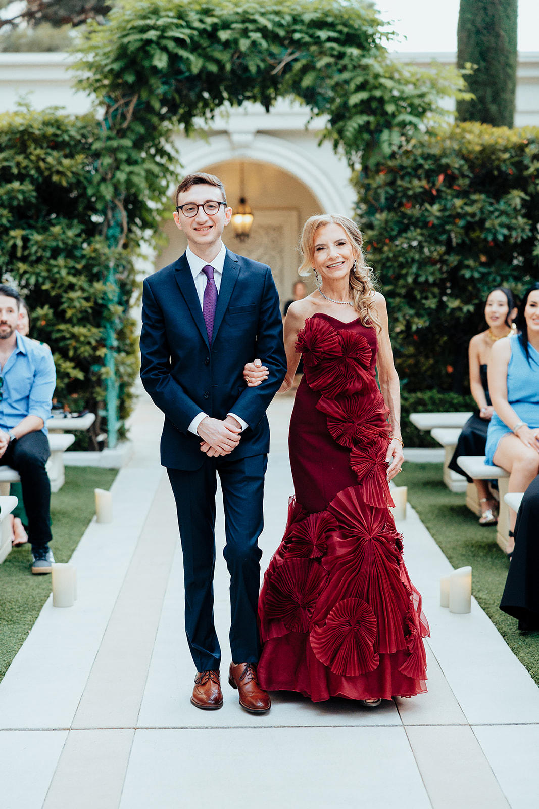 Mother in Burgundy Dress Walking Down Aisle with Escort