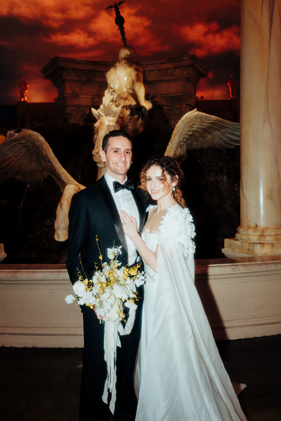 Bride and groom posing in front of the grand fountain at Caesars Palace during their Las Vegas wedding.