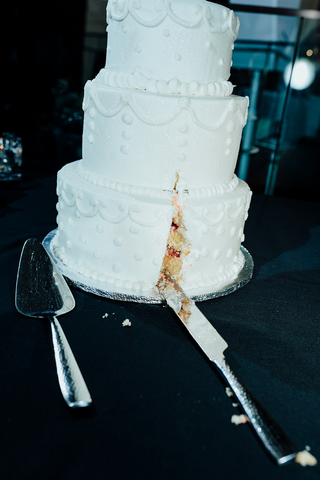 Close-up of a sliced white wedding cake with a knife and server on a table during a Las Vegas wedding reception.