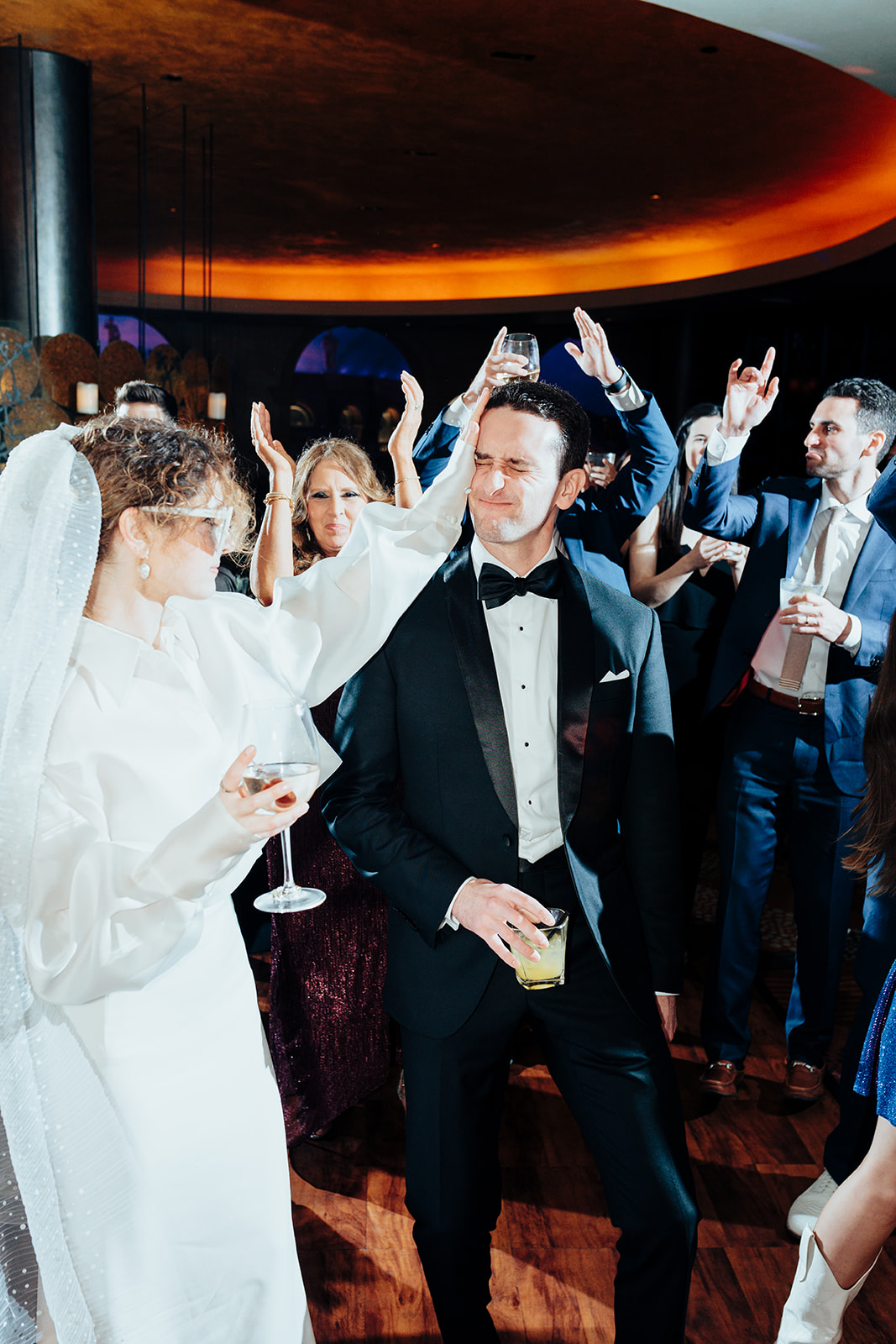 Bride playfully dancing with the groom on the dance floor surrounded by cheering guests during a lively Las Vegas wedding reception at Caesars Palace.