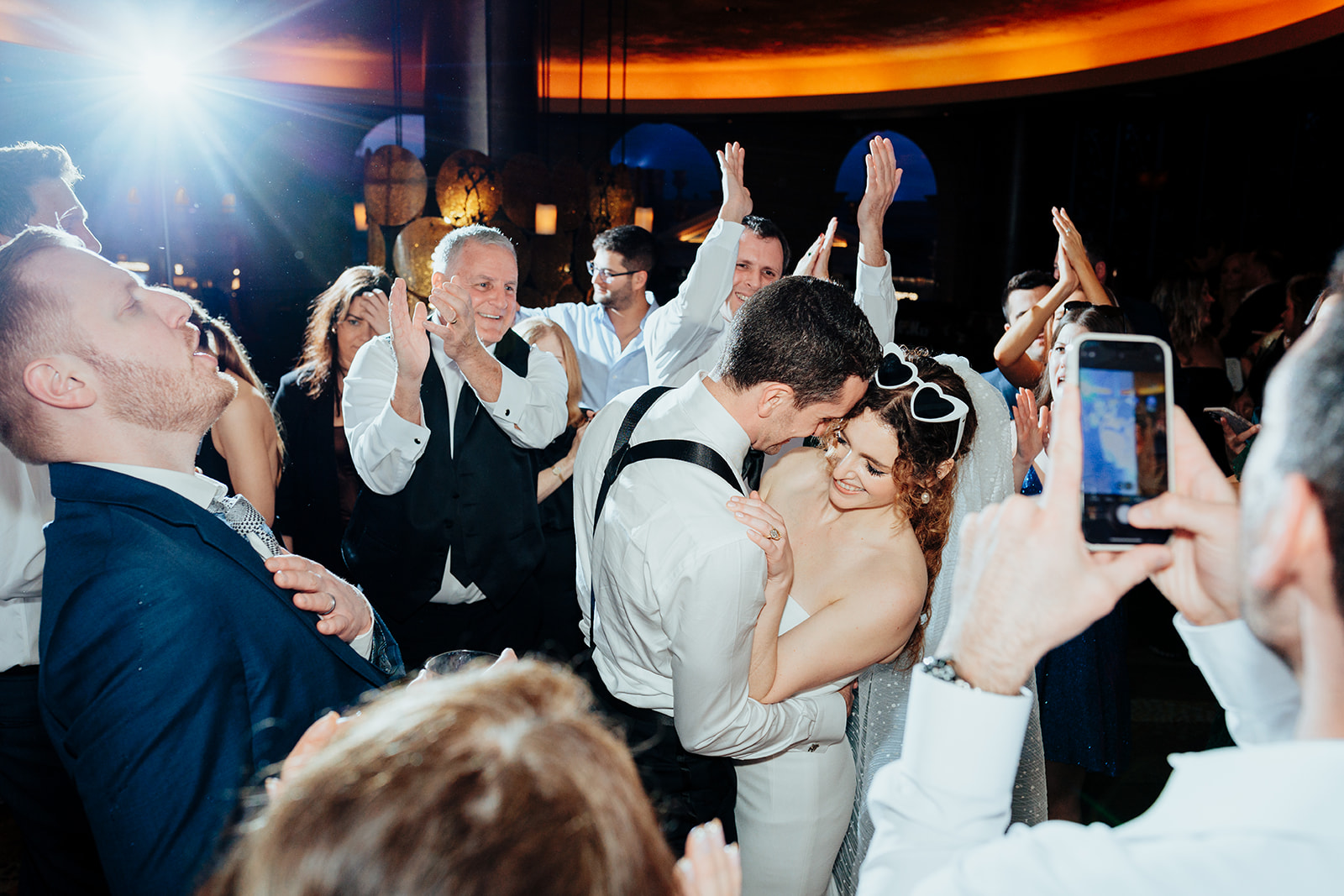 Bride and groom laughing and dancing together surrounded by cheering guests during their Las Vegas wedding reception at Caesars Palace.