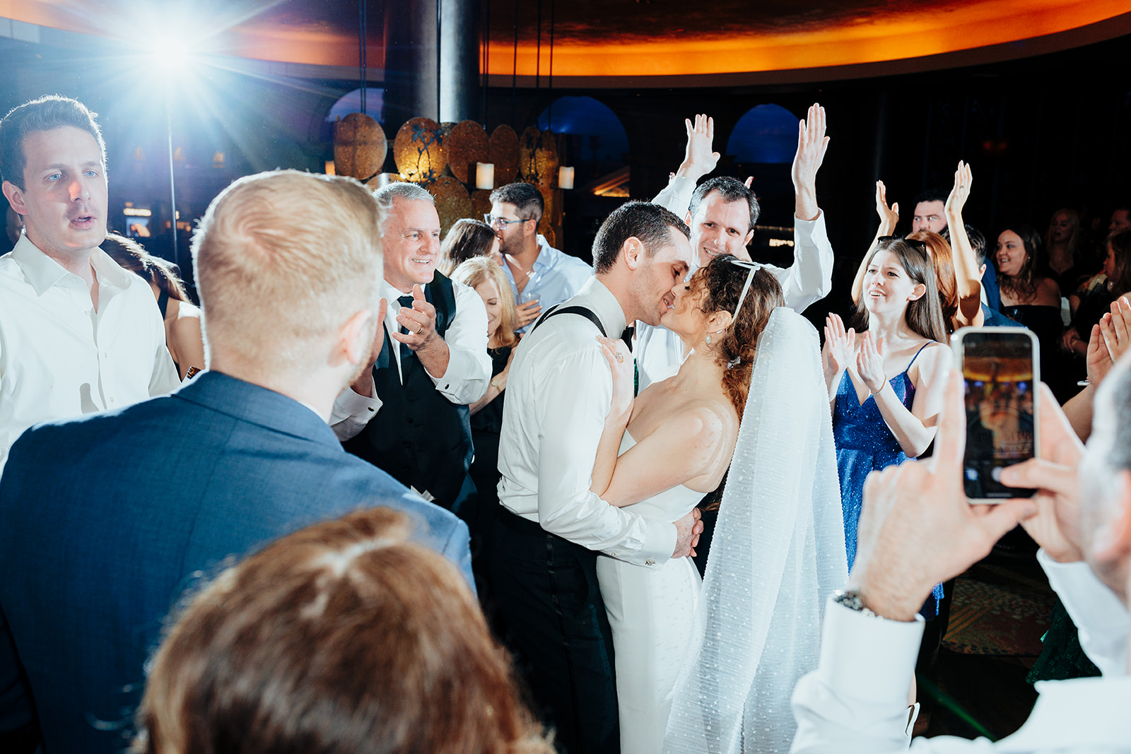 Bride and groom sharing a romantic kiss on the dance floor surrounded by guests during their Las Vegas wedding reception.