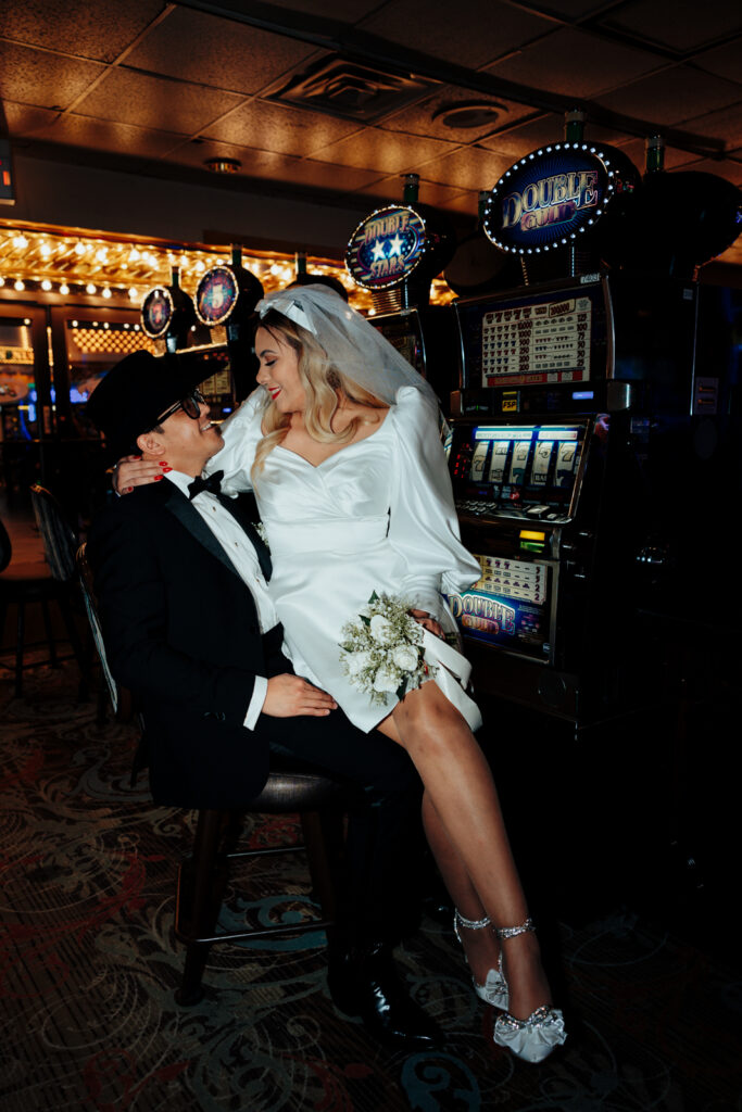 Bride Sitting on Groom’s Lap in Front of Slot Machines