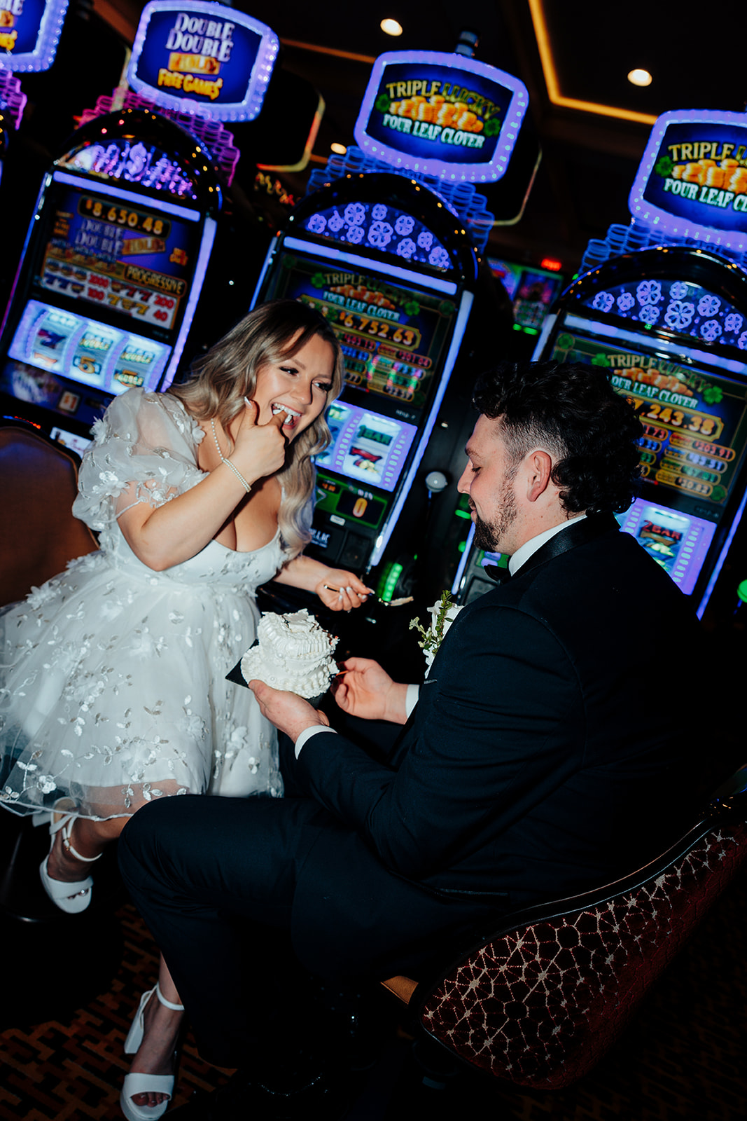 Bride and groom sharing cake at Golden Nugget casino after Little White Wedding Chapel elopement, with slot machines in the background.