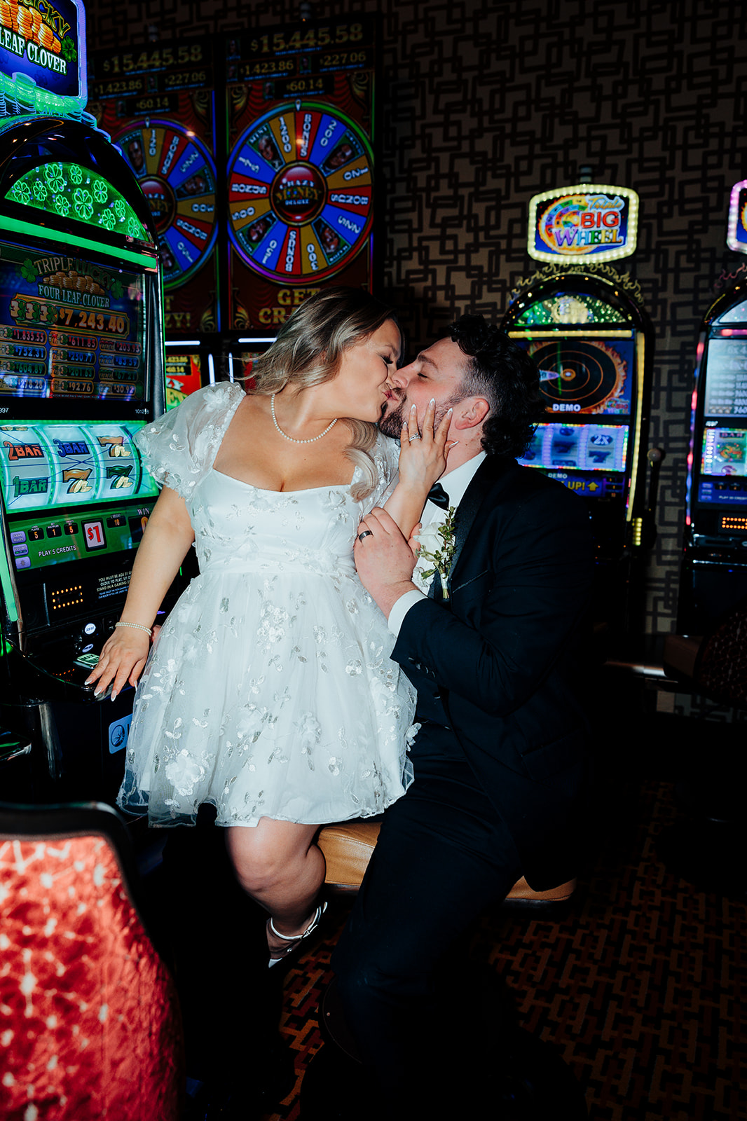 Bride and groom kissing at Golden Nugget casino after Little White Wedding Chapel elopement, surrounded by slot machines.