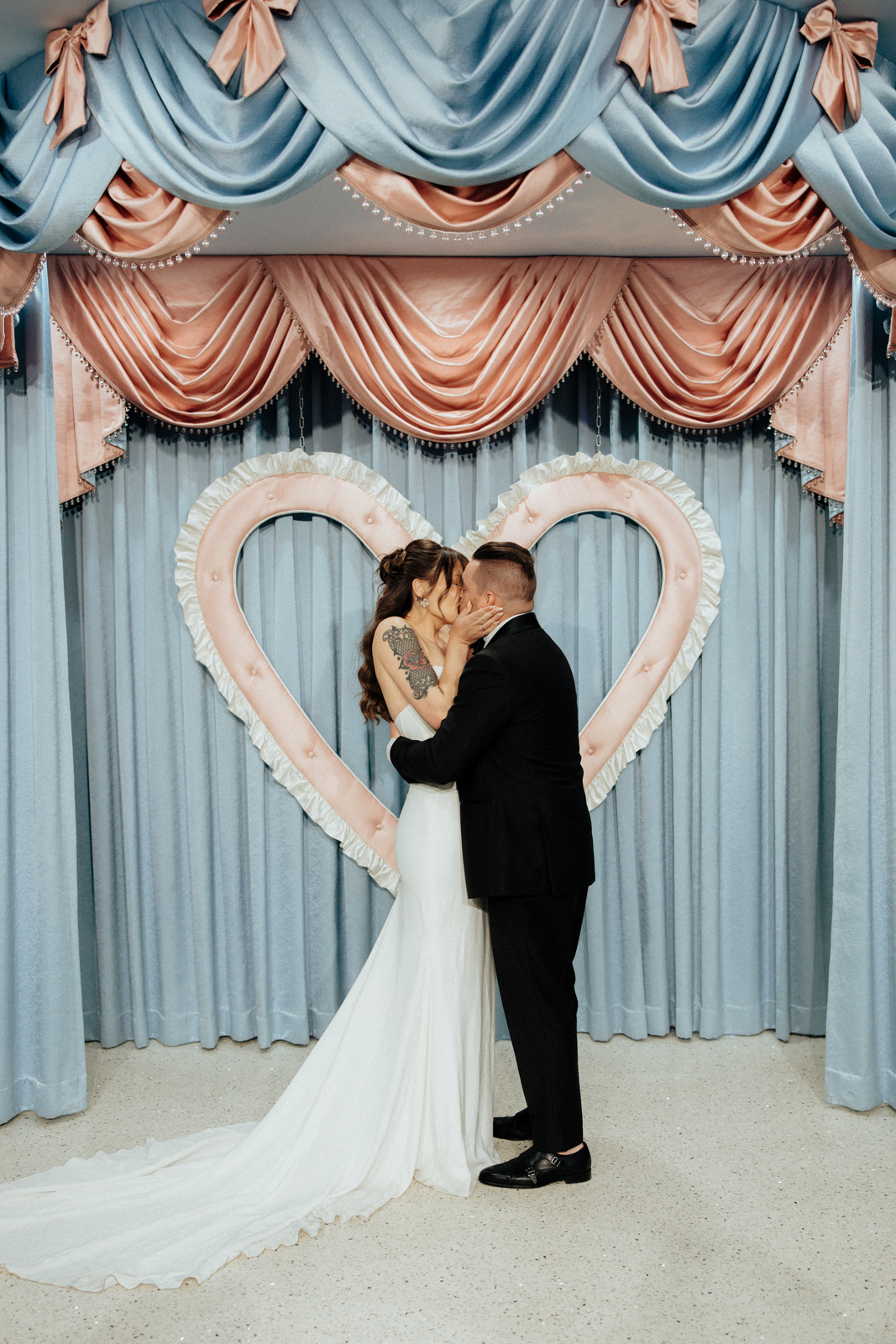A Kiss in Front of a heart backdrop at Sure Thing Chapel in Las Vegas.